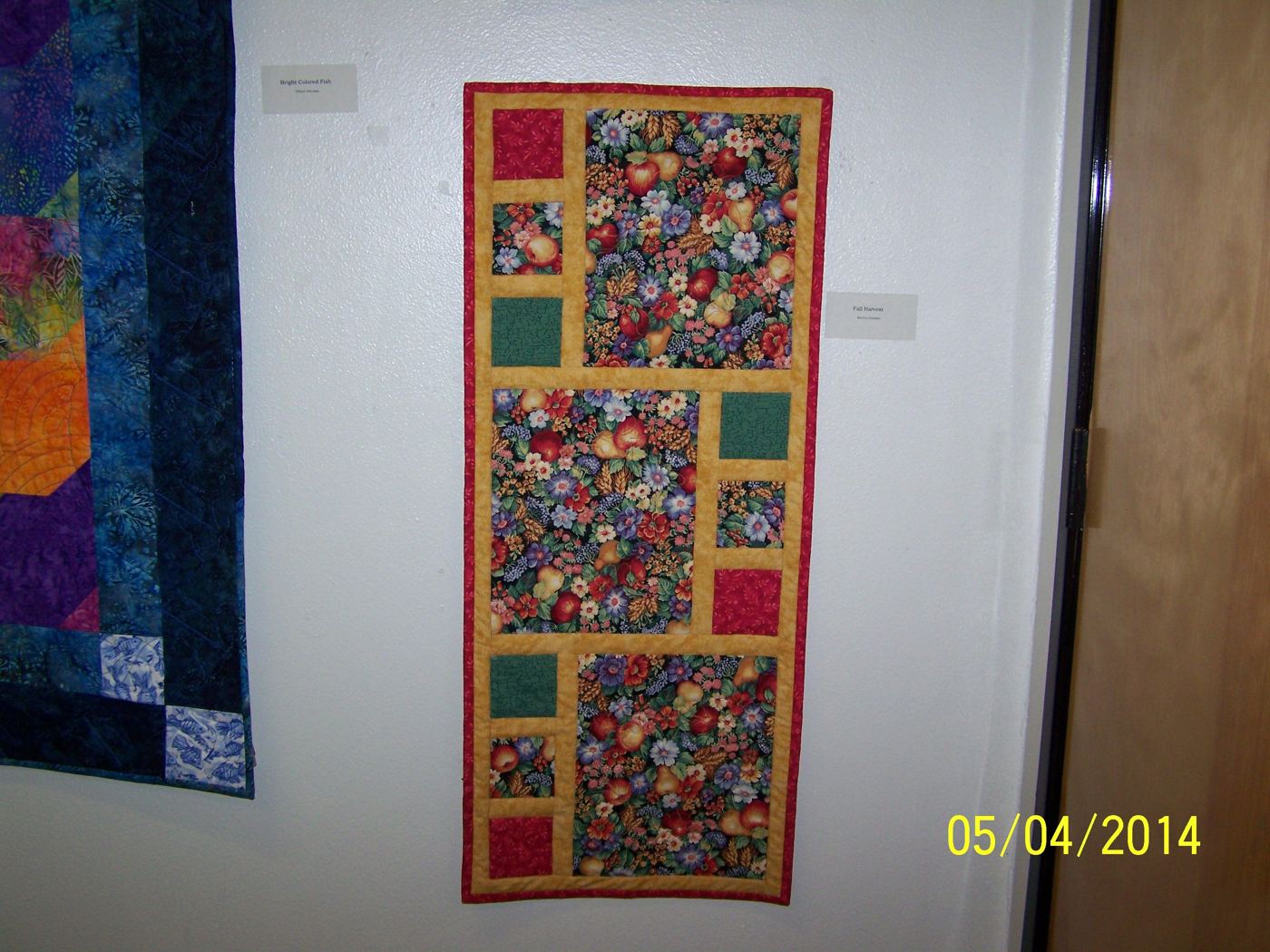 Fruit and flower table runner hung on a show wall.